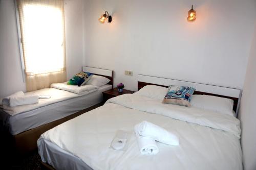 two beds in a hotel room with white sheets at Halikarnas Pansiyon in Bodrum City