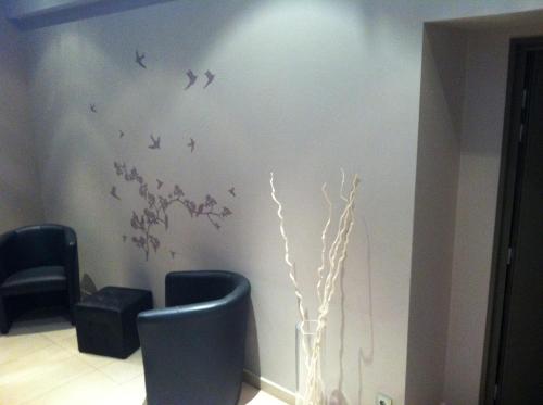 a room with two chairs and birds on the wall at Le Relais des Bergers in Saint-Martin-en-Haut