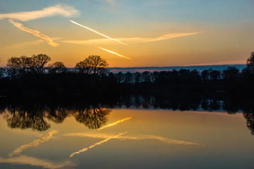 a sunset over a lake with trees in the background at Waldhotel Schipp-Hummert in Emsdetten