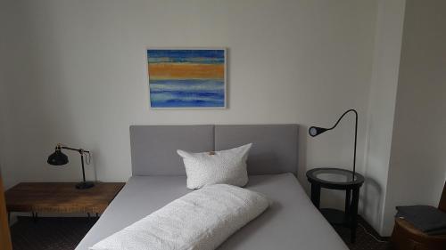 a bed with a pillow and a painting on the wall at Schillers Hotel & Café - GARNI - in Lüdenscheid