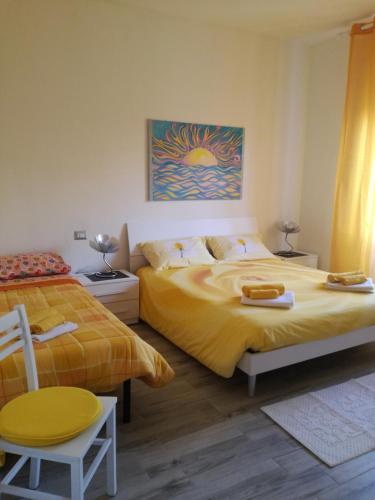 a bedroom with two beds and a chair at House of colours - Relax, arte e confort per coppie, famiglie e gruppi in Alghero