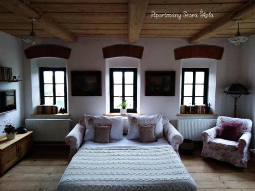 a bedroom with a bed and a couch and windows at Apartmány Stará Škola in Krásná Lípa
