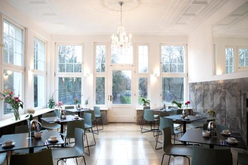 a dining room with tables and chairs and windows at Hotel Schloss Teutschenthal in Teutschenthal