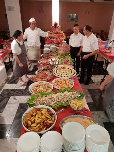 een groep mensen die rond een tafel met eten staan bij Hotel Ginevra in Riccione