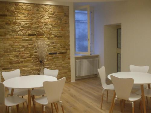 two tables and chairs in a room with a brick wall at B&B Dimora Damiani in Montefiore dellʼAso