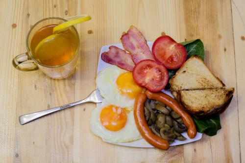 a plate of breakfast food with eggs and bread and a cup of tea at Ashtarak Garden GuestHouse in Ashtarak