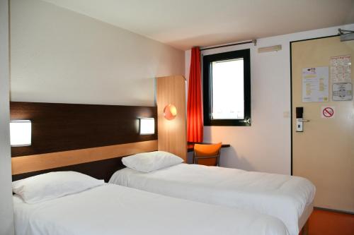 una camera d'albergo con due letti e una finestra di Premiere Classe Nevers Varennes Vauzelles a Varennes-Vauzelles