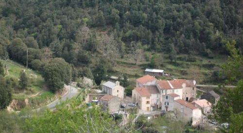 un groupe de maisons sur une colline avec une route dans l'établissement A Stella, une cabane de berger pour une expérience insolite, à Santa-Lucia-di-Mercurio