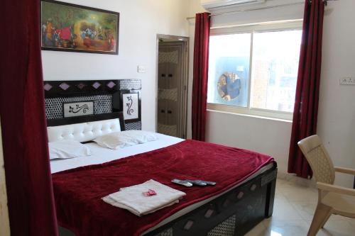 a bedroom with a large bed with a red blanket at Hotel Sunset in Orchha
