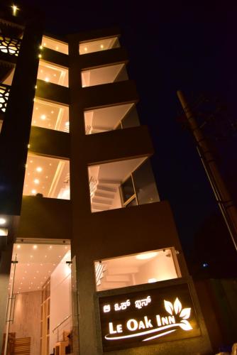 a building with a lit up sign in front of it at Le Oak Inn in Mysore