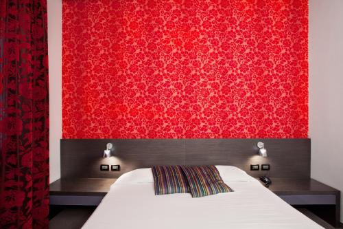 a bedroom with a bed with a red wall at MA Hotel in Santa Margherita Ligure