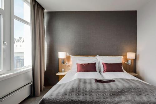 a bedroom with a large bed with two red pillows at Quality Hotel Residence in Sandnes