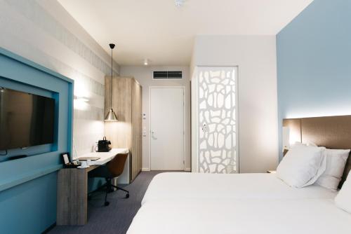 a bedroom with a bed and a desk and a television at Fletcher Hotel-Restaurant Weert in Weert