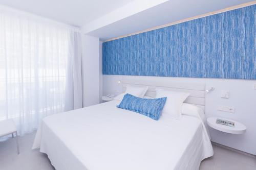 a bedroom with a white bed and a blue wall at Reverence Mare Hotel - Adults Only in Palmanova