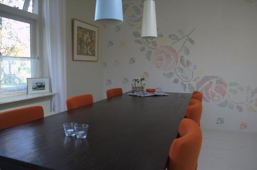 a dining room with a black table and orange chairs at Logement-B&B Safier in Joure