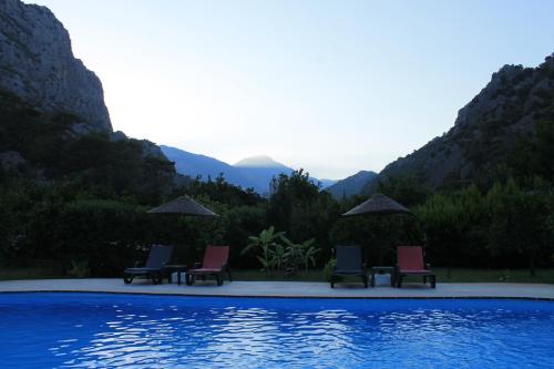 three chairs and umbrellas next to a swimming pool at Portalimo Lodge Hotel - Adult Only +12 in Cıralı