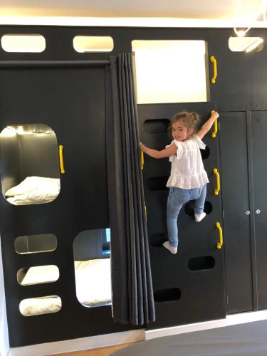 a little girl is sitting on a bunk bed in a bus at Willow Court Farm Studio South & Petting Farm, 8 mins from Legoland & Windsor, 15 mins from Lapland UK in Windsor