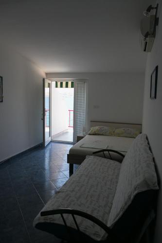 a room with two beds and a door to a patio at Apartmani Herceg in Karlobag