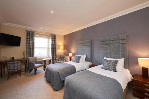 a hotel room with two beds and a desk at Royal Golf Hotel in Dornoch