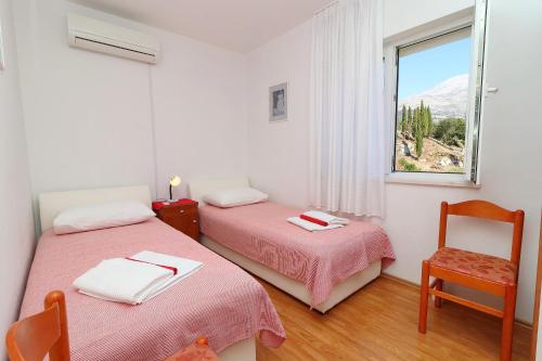 two beds in a room with a window and a chair at Guest House Franica & Pero Lobrovic in Slano