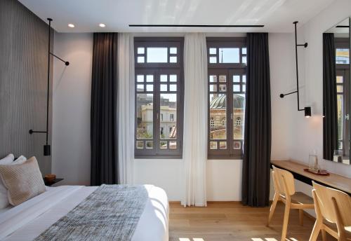 a bedroom with a bed and a desk and windows at InnAthens in Athens