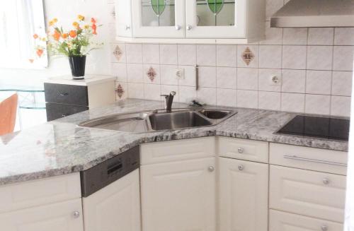 eine Küche mit einem Waschbecken und weißen Schränken in der Unterkunft Ferien-Appartement am Schloßsee in Salem