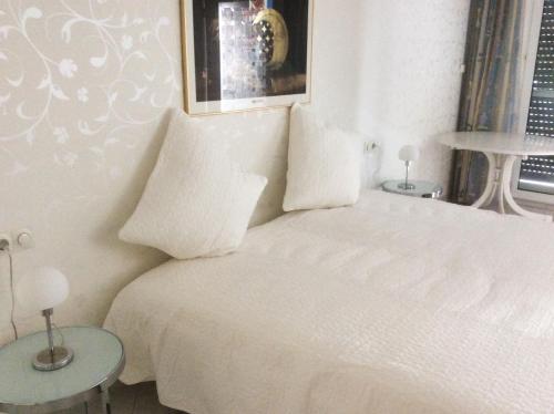 ein weißes Schlafzimmer mit einem weißen Bett und 2 Tischen in der Unterkunft Ferien-Appartement am Schloßsee in Salem