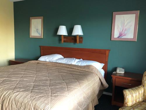a bedroom with a bed and two lamps on the wall at Americas Best Inn - Savannah I-95 in Savannah