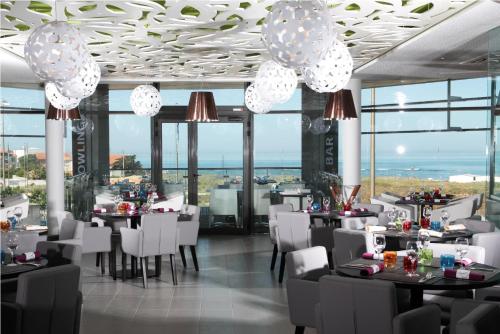 a restaurant with tables and chairs and large windows at Les Terrasses de l'Océan in Saint-Hilaire-de-Riez