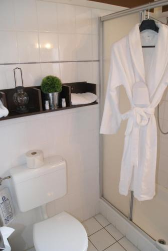 uma casa de banho com uma toalha branca pendurada na porta do chuveiro em Landhotel Berggaststätte Bickenriede em Anrode