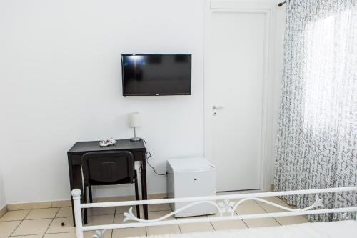 a room with a tv on the wall and a chair at Veda elegant rooms in Fiumefreddo di Sicilia