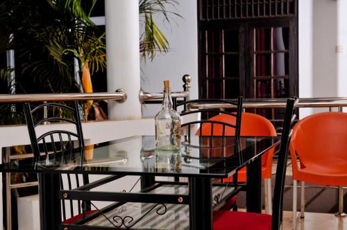 una mesa de cristal con sillas naranjas y una botella en ella en Myr-o Homestay, en Anuradhapura