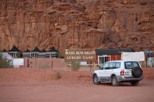 a white truck parked in front of a stone wall at Wadi Rum Night Luxury Camp in Wadi Rum