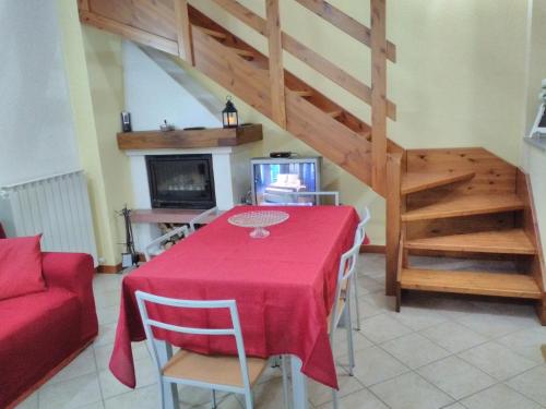 a dining room with a red table and a staircase at LA CASA DEL BORGO in Aviatico