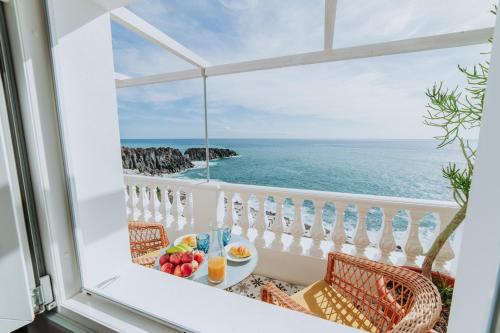 a breakfast table on a balcony with a view of the ocean at Casa da Praia in Câmara de Lobos