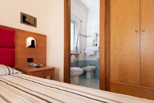 a bedroom with a bed and a bathroom with a toilet at Hotel Paradiso in Grottammare