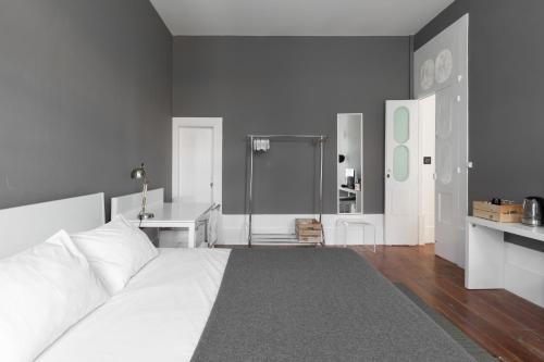 a bedroom with a large white bed and a desk at GuestReady - Astern Innvict - Street view in Porto