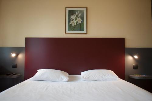 a bed with two white pillows on top of it at Mape hôtel in Dampierre-en-Burly