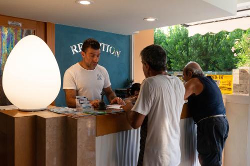 a group of men standing around a counter at Hotel Paradiso in Grottammare