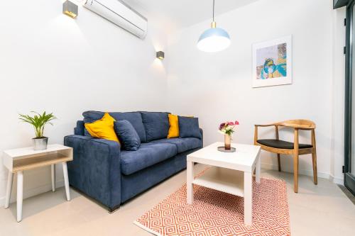 a living room with a blue couch and two tables at Emanuel Boutique in Jerusalem
