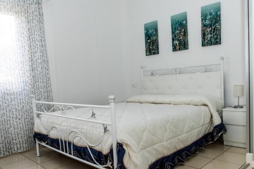 a white bed in a white bedroom with two pictures on the wall at Veda elegant rooms in Fiumefreddo di Sicilia