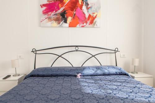 a bedroom with a bed with a blue comforter and a painting at Veda elegant rooms in Fiumefreddo di Sicilia