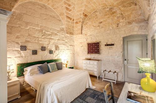 a bedroom with a bed and a stone wall at Masseria Cervarolo in Ostuni