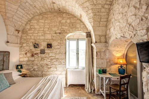 a bedroom with a bed and a window in a stone wall at Masseria Cervarolo in Ostuni