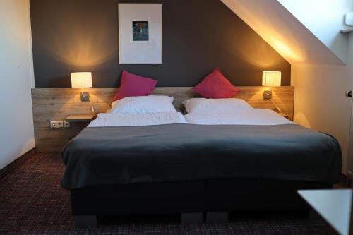 een slaapkamer met een groot bed met roze kussens bij Ilvericher Hof in Meerbusch