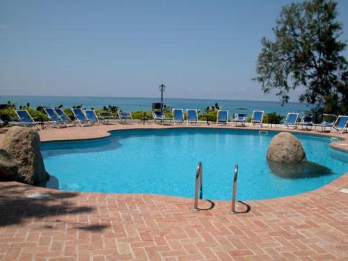 a swimming pool with rocks and chairs and the ocean at Esclusiva villa sul mare Tropea in Parghelia