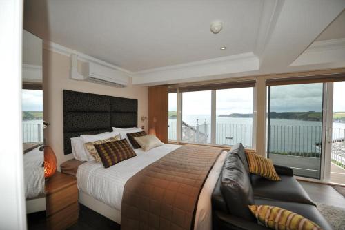a bedroom with a bed and a couch and windows at Porth Avallen Hotel in St Austell
