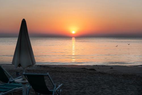 an umbrella and chairs on the beach at sunset at Hotel Paradiso in Grottammare