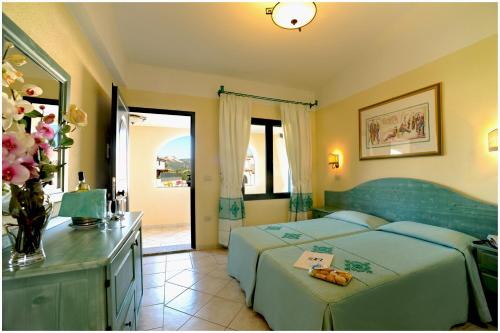 ein Schlafzimmer mit 2 Betten und einem Tisch mit Blumen darauf in der Unterkunft Residence Cala Liberotto in Cala Liberotto