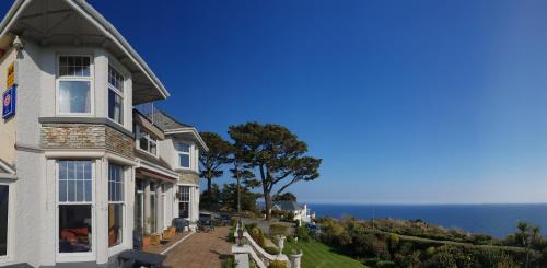 a white house with the ocean in the background at Porth Avallen Hotel in St Austell
